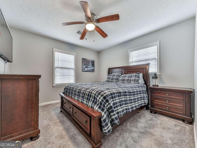 bedroom featuring light carpet, a textured ceiling, and ceiling fan