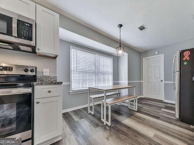 kitchen with white cabinetry, stainless steel appliances, decorative light fixtures, and dark wood-type flooring