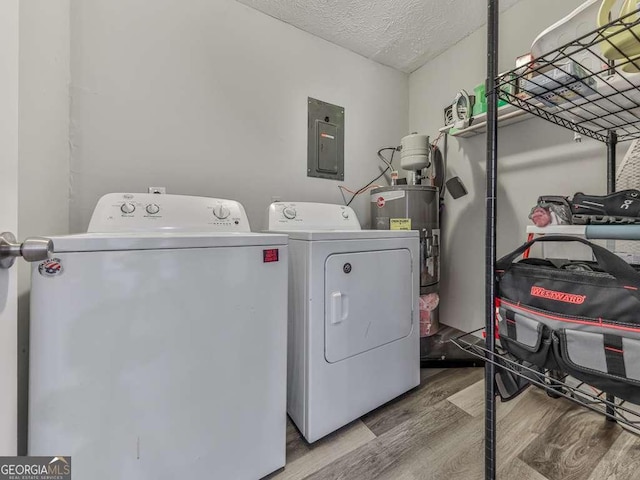 washroom featuring hardwood / wood-style flooring, water heater, electric panel, independent washer and dryer, and a textured ceiling