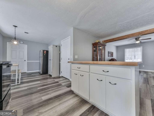 kitchen with dark hardwood / wood-style floors, white cabinetry, stainless steel fridge, hanging light fixtures, and range