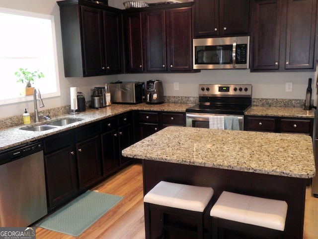 kitchen featuring appliances with stainless steel finishes, light stone countertops, sink, and a kitchen island