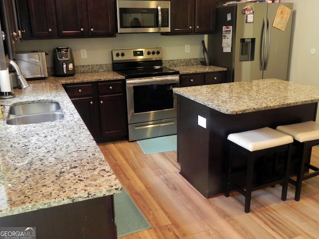 kitchen with appliances with stainless steel finishes, a kitchen breakfast bar, a center island, and sink