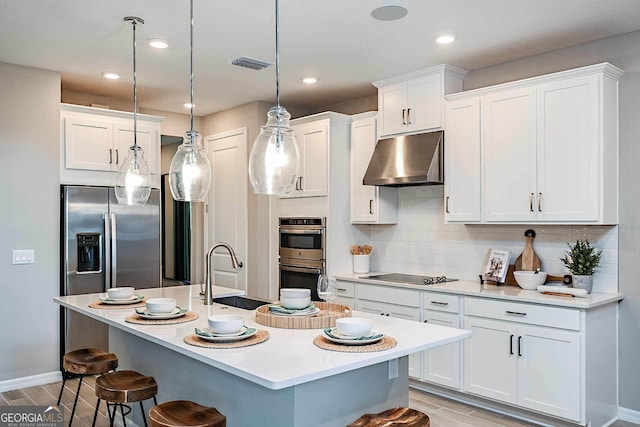 kitchen with a breakfast bar area, hanging light fixtures, appliances with stainless steel finishes, white cabinets, and backsplash