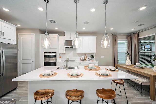 kitchen featuring appliances with stainless steel finishes, decorative light fixtures, and white cabinets