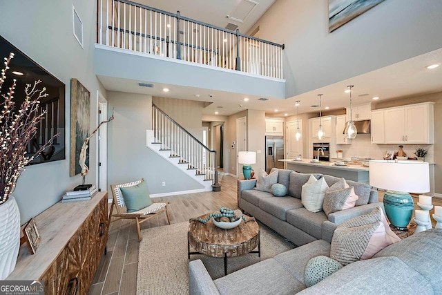 living room featuring a towering ceiling and light hardwood / wood-style floors