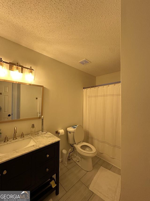 bathroom with walk in shower, vanity, toilet, and a textured ceiling