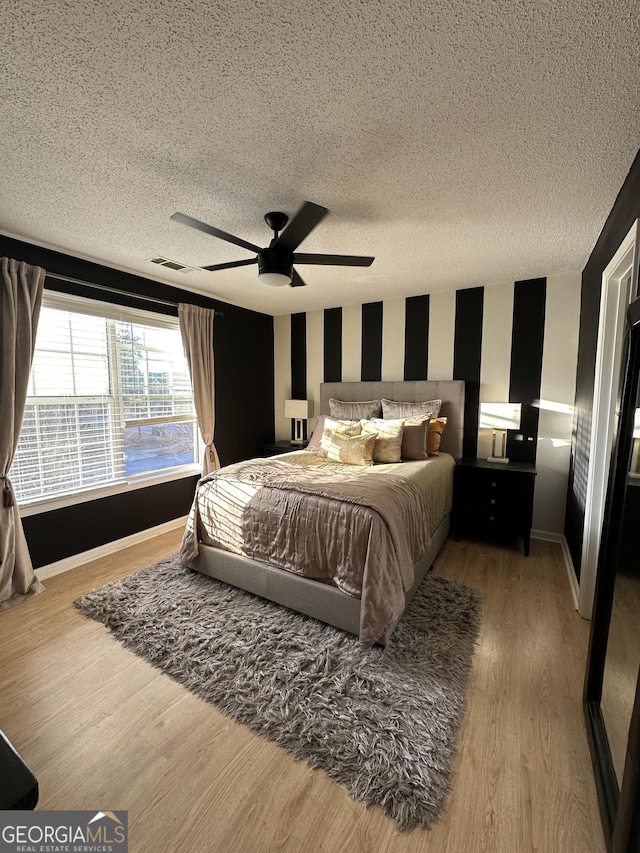 bedroom with hardwood / wood-style flooring, ceiling fan, and a textured ceiling