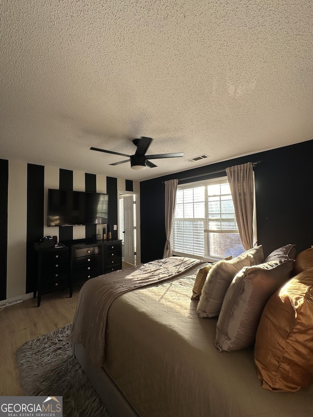 bedroom featuring ceiling fan, wood-type flooring, and a textured ceiling