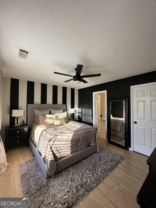 bedroom featuring hardwood / wood-style floors, a textured ceiling, and ceiling fan