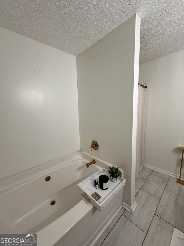 bathroom featuring a washtub and a textured ceiling