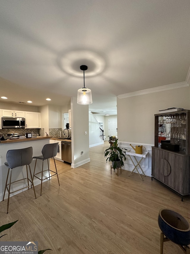 kitchen featuring appliances with stainless steel finishes, a breakfast bar area, white cabinets, hanging light fixtures, and kitchen peninsula