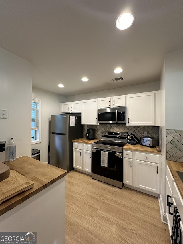 kitchen featuring white cabinetry, stainless steel appliances, butcher block counters, and light wood-type flooring