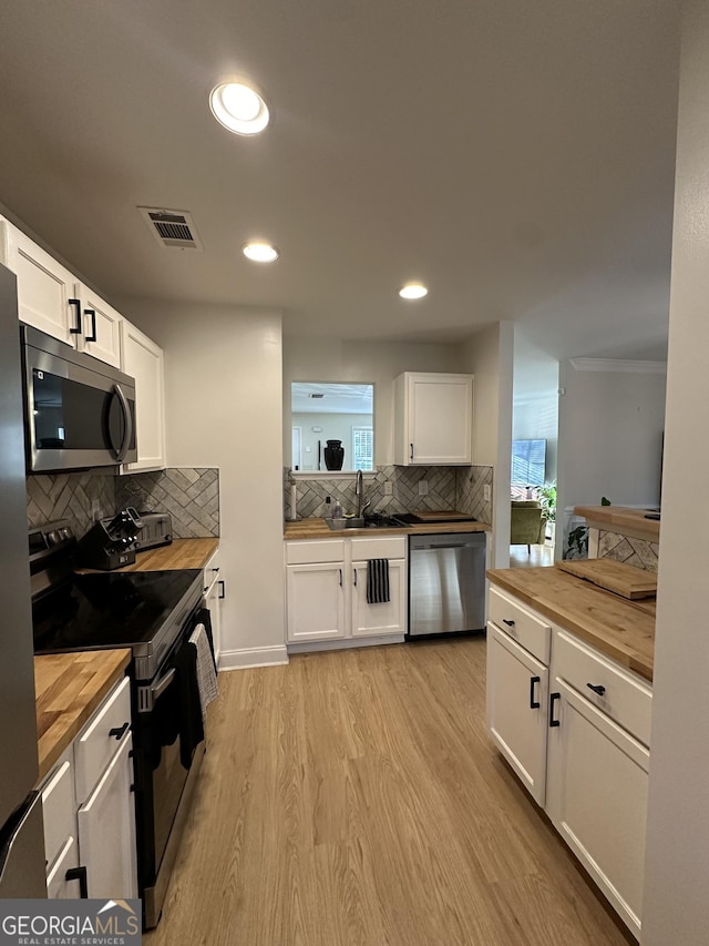 kitchen featuring wood counters, stainless steel appliances, and white cabinets