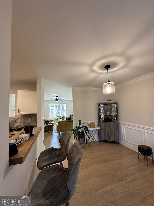 dining space with ornamental molding and light hardwood / wood-style floors