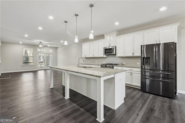 kitchen featuring white cabinetry, sink, hanging light fixtures, stainless steel appliances, and a center island with sink