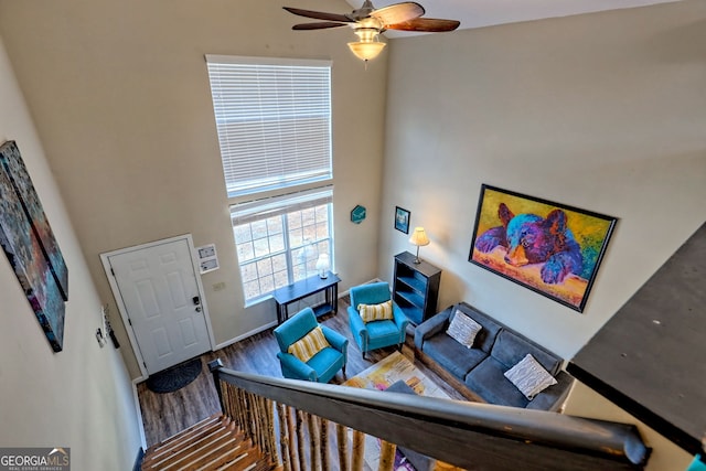 living room with ceiling fan, a towering ceiling, and wood-type flooring