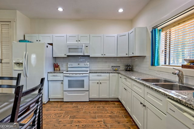 kitchen with light stone counters, white appliances, sink, and white cabinets