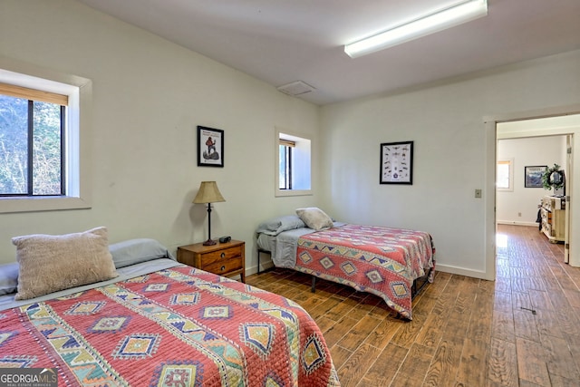 bedroom featuring multiple windows and dark hardwood / wood-style flooring