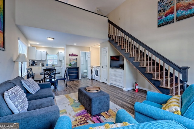 living room with hardwood / wood-style flooring, washer and dryer, and a high ceiling