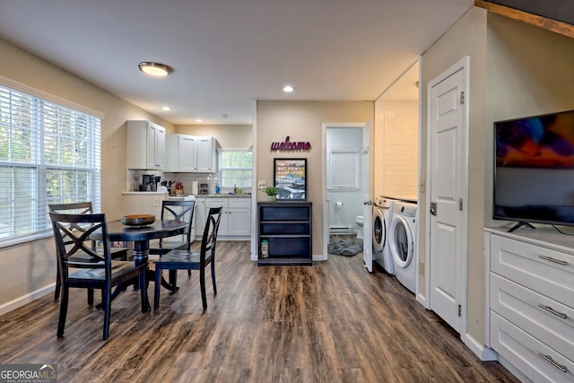 kitchen with dark wood-type flooring, washing machine and clothes dryer, baseboard heating, and white cabinets