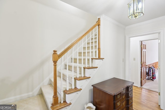 stairs featuring ornamental molding, wood-type flooring, and an inviting chandelier