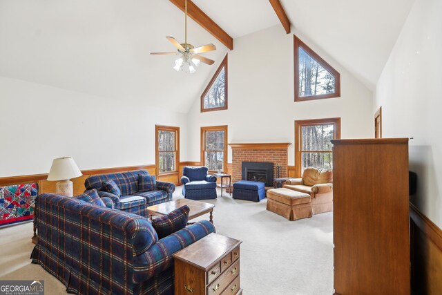 carpeted living room featuring a brick fireplace, high vaulted ceiling, beamed ceiling, and ceiling fan