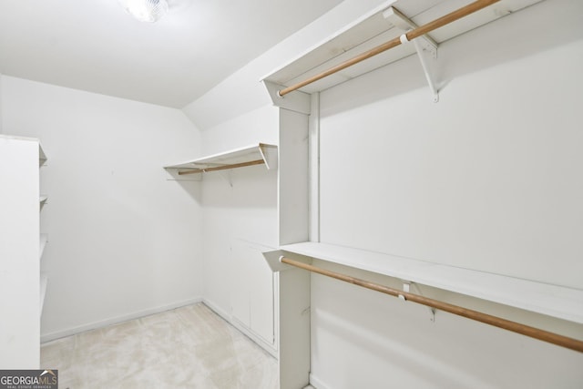 spacious closet featuring light colored carpet and lofted ceiling