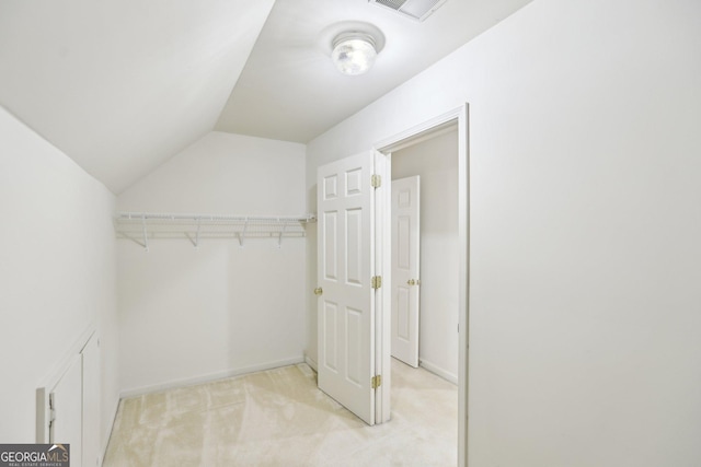 walk in closet featuring lofted ceiling and light colored carpet