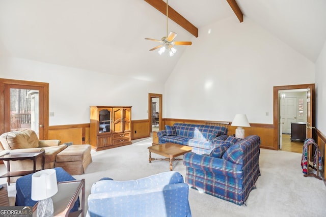 carpeted living room featuring beamed ceiling, ceiling fan, wooden walls, and high vaulted ceiling