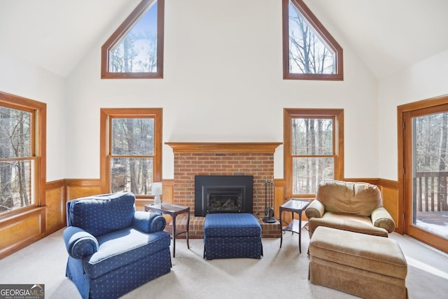 carpeted living room with a brick fireplace, plenty of natural light, and high vaulted ceiling