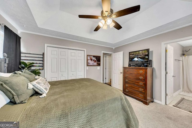 bedroom featuring ceiling fan, a textured ceiling, a raised ceiling, light carpet, and a closet