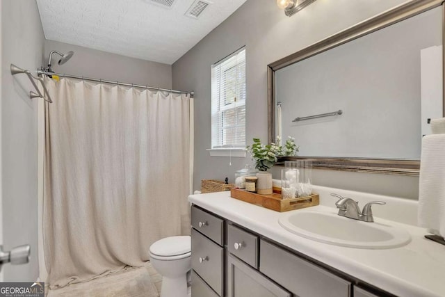 bathroom with vanity, toilet, curtained shower, and a textured ceiling