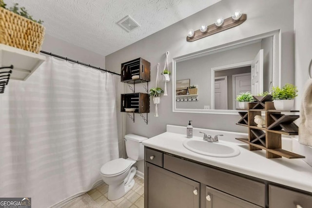 bathroom with vanity, toilet, and a textured ceiling