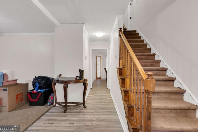 staircase with crown molding, a textured ceiling, and hardwood / wood-style flooring