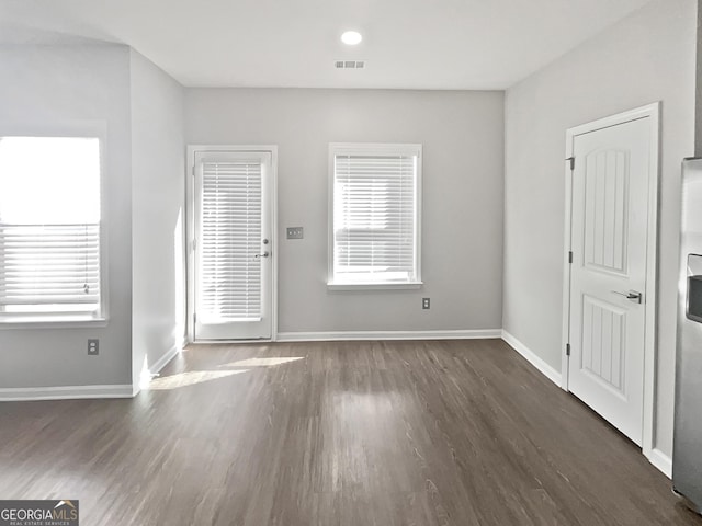 unfurnished room with a healthy amount of sunlight and dark wood-type flooring