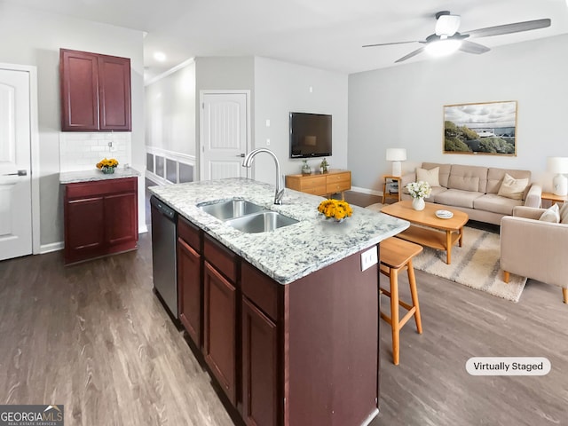 kitchen with dark hardwood / wood-style floors, dishwasher, sink, backsplash, and a kitchen island with sink