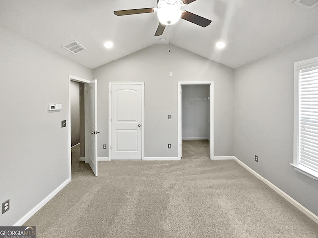 unfurnished bedroom featuring lofted ceiling, a spacious closet, light carpet, and ceiling fan