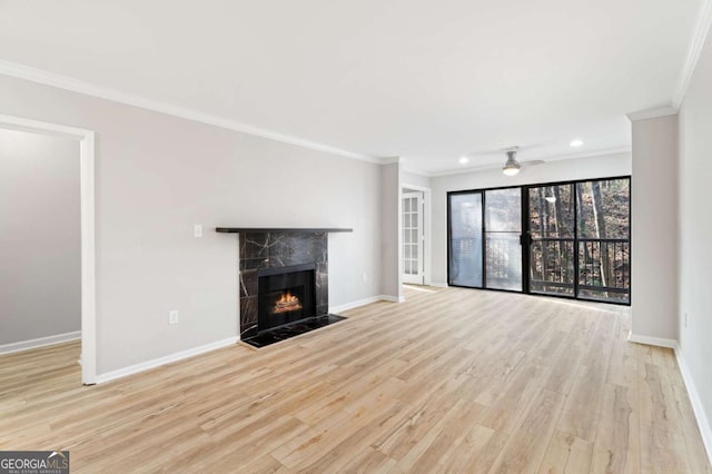 unfurnished living room with crown molding, ceiling fan, a tiled fireplace, and light hardwood / wood-style floors