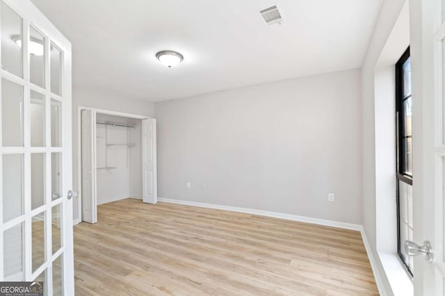 unfurnished bedroom with french doors, a closet, and light hardwood / wood-style flooring