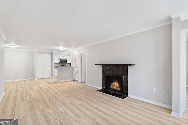 unfurnished living room featuring crown molding, a premium fireplace, and light wood-type flooring