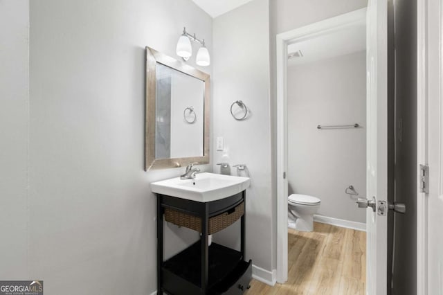 bathroom featuring vanity, wood-type flooring, and toilet