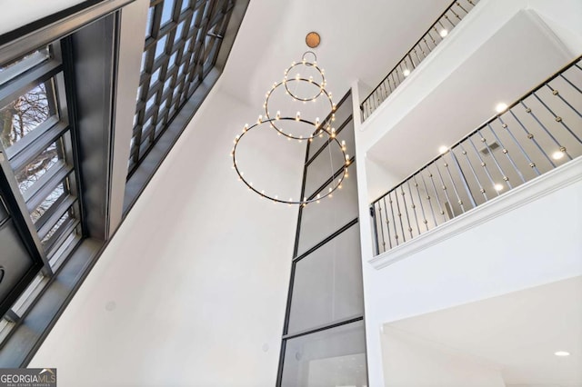 stairs with an inviting chandelier and a towering ceiling