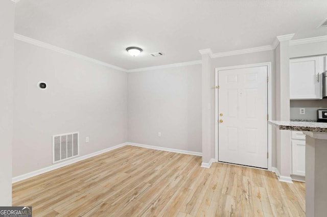 interior space featuring light stone counters, crown molding, white cabinets, and light wood-type flooring