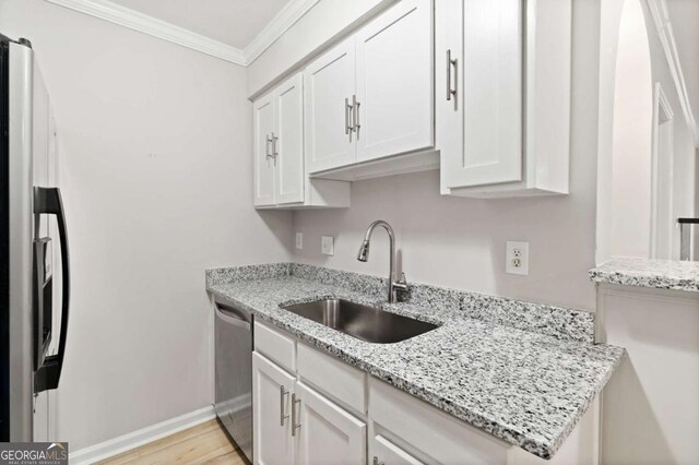 kitchen featuring sink, appliances with stainless steel finishes, white cabinetry, ornamental molding, and light stone countertops