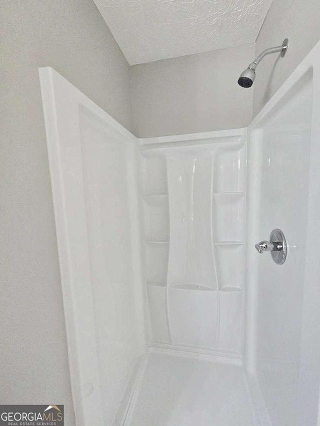 bathroom featuring a textured ceiling and walk in shower