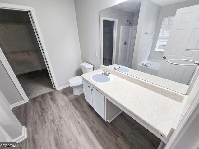 full bathroom featuring hardwood / wood-style flooring, vanity, separate shower and tub, and toilet