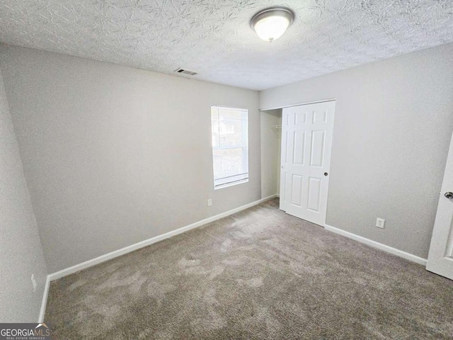 unfurnished bedroom with carpet floors, a closet, and a textured ceiling