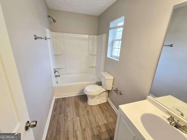 full bathroom featuring washtub / shower combination, hardwood / wood-style flooring, vanity, toilet, and a textured ceiling