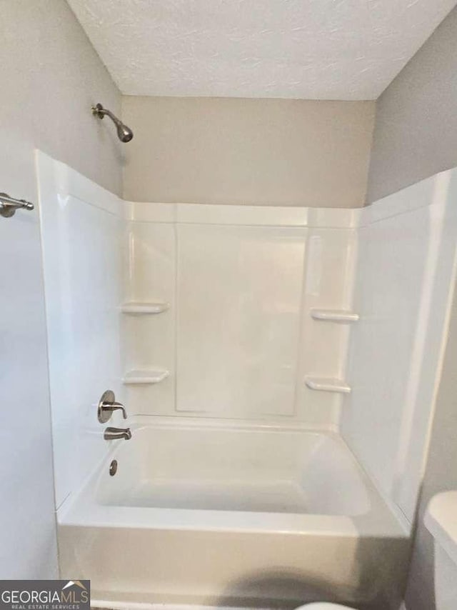 bathroom featuring shower / bath combination, a textured ceiling, and toilet