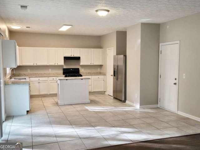 kitchen with sink, range, a center island, stainless steel fridge, and white cabinets